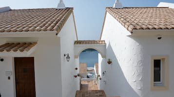 A narrow pathway leading to a building with a tiled roof and a door marked with the number 007.