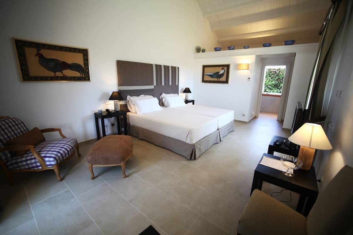 Ein Schlafzimmer mit einem Bett, einem Nachttisch, einem Sessel, einer Bank und einer Lampe.