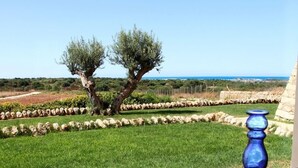 Un tavolo con vista sul mare, un vaso blu e pasticcini su un vassoio.