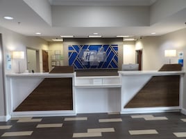 A reception area with a modern design, featuring a reception desk, a blue geometric wall decoration, and a clean, organized layout.