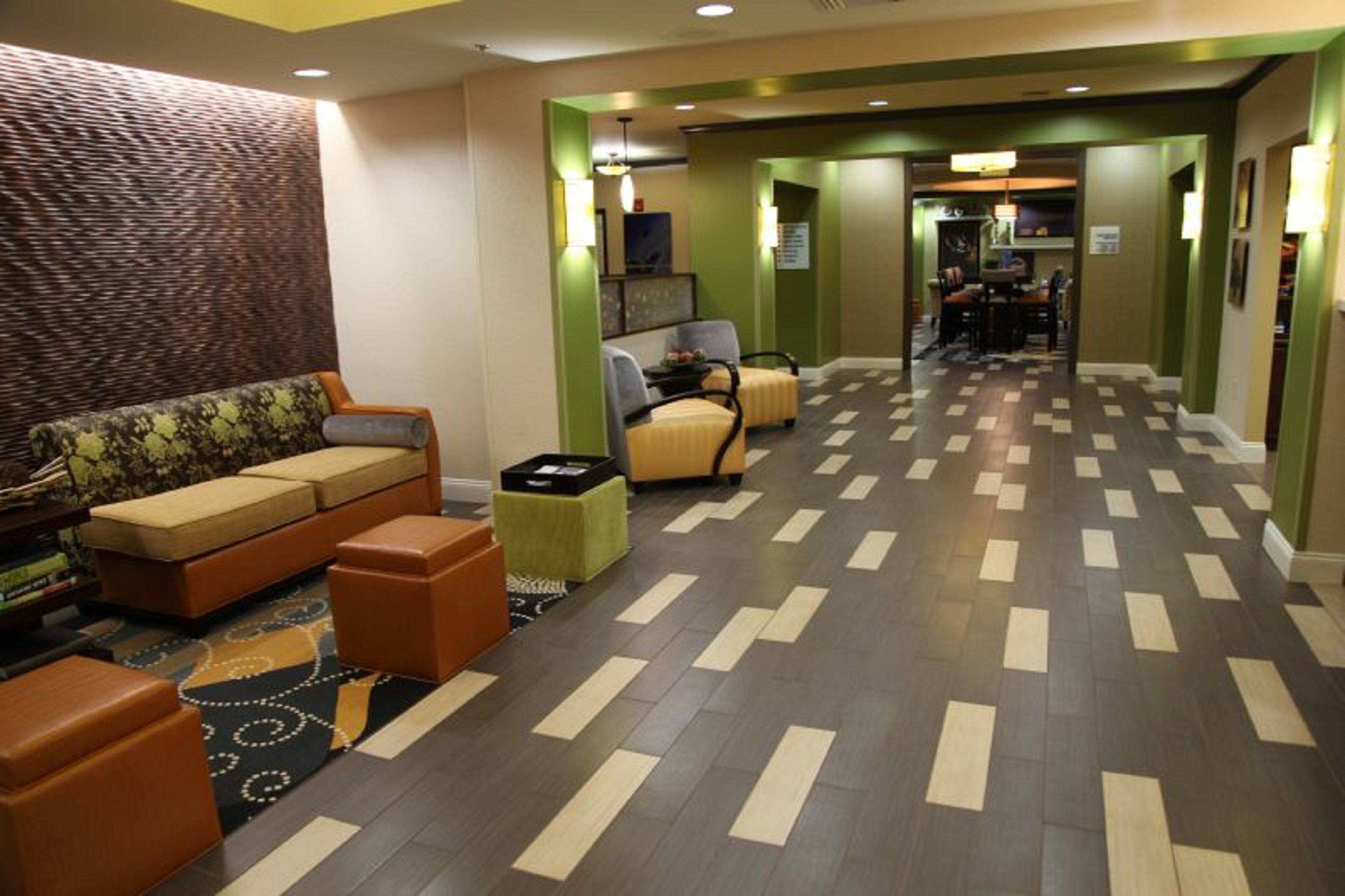 A hotel lobby with a sofa, armchairs, a small table, and a patterned rug.