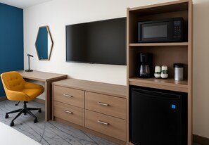 A modern hotel room with a desk, chair, flat-screen TV, microwave, coffee maker, and mini-fridge. - Holiday Inn Express & Suites Huntsville Airport by IHG (Madison)
