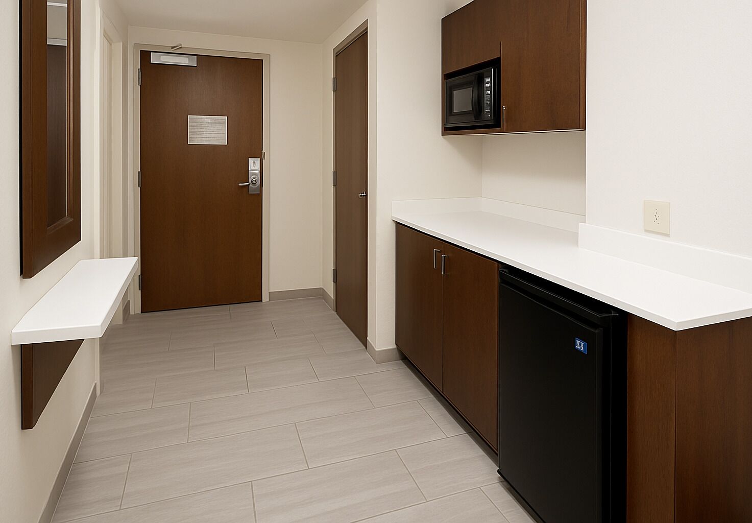 A hallway with a microwave above a wooden cabinet, a black dishwasher, and a white countertop.