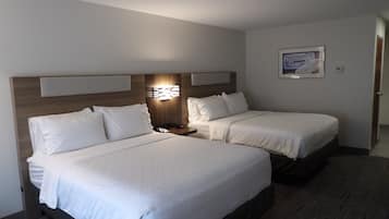 A hotel room with two beds, a nightstand, a wall-mounted light, and a framed picture.