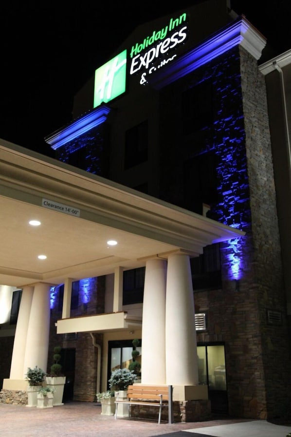 Entrada de un hotel Holiday Inn Express, con un letrero visible, un espacio cubierto con columnas y plantas en macetas.