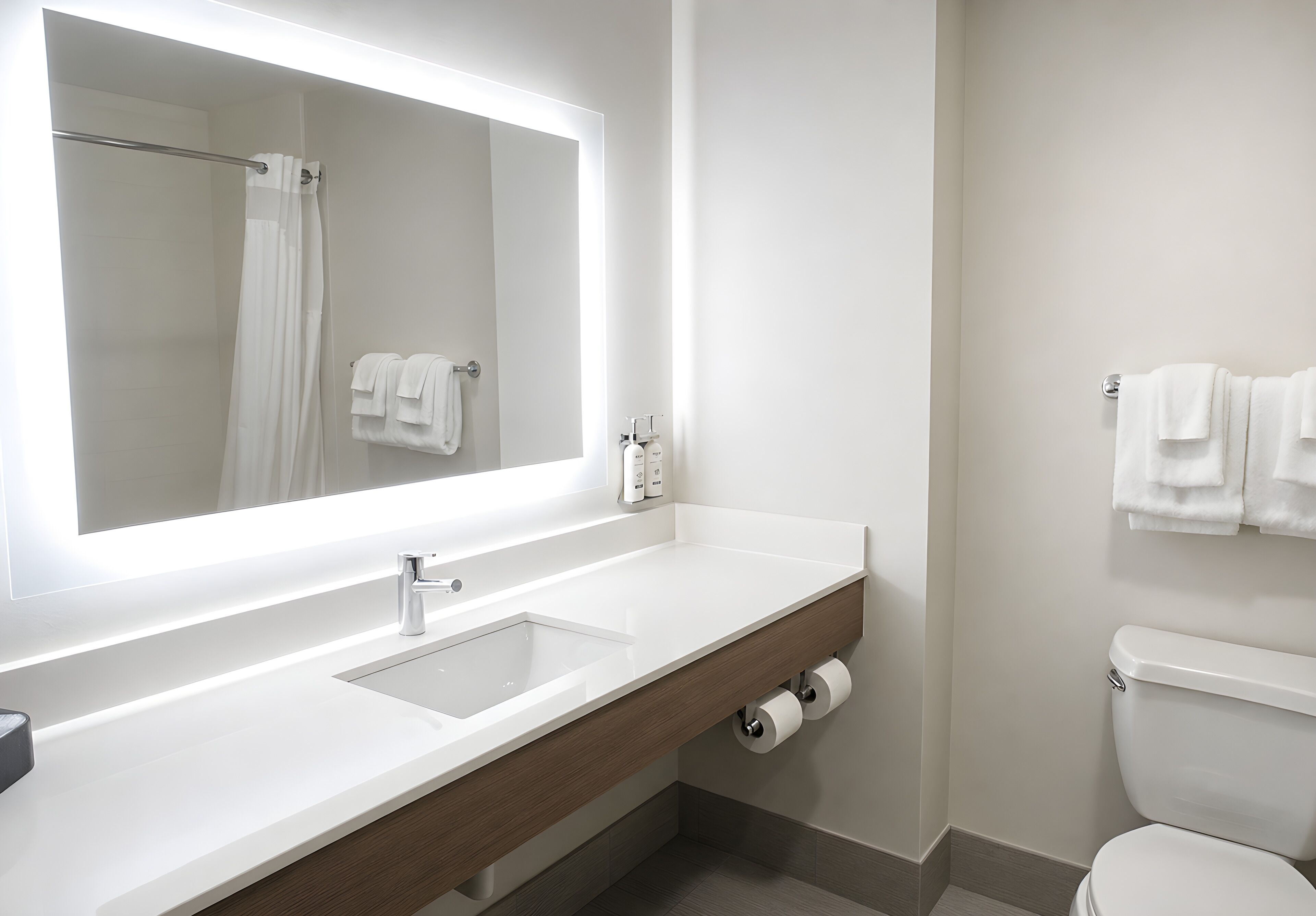 A modern bathroom with a large mirror, a sink, a toilet, and a towel rack.
