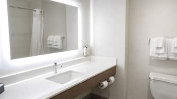 A modern bathroom with a large mirror, a sink, a toilet, and a towel rack.