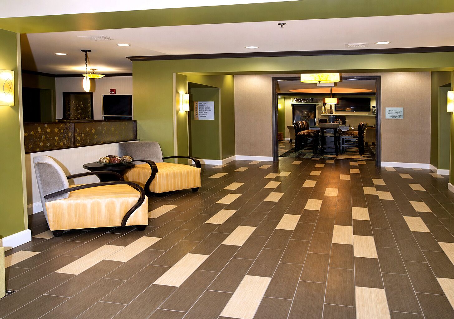 A hotel lobby with a check-in counter, seating area, and a dining area.