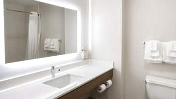 A modern bathroom with a large mirror, a sink, a toilet, and a shower curtain.