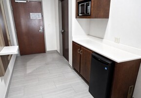 Uma cozinha com micro-ondas, máquina de lavar louça e bancada branca.