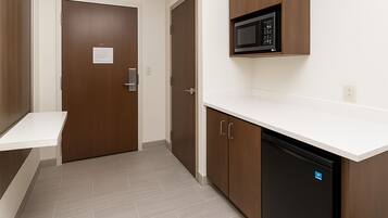 Una kitchenette equipada con microondas, lavavajillas y armarios de madera.