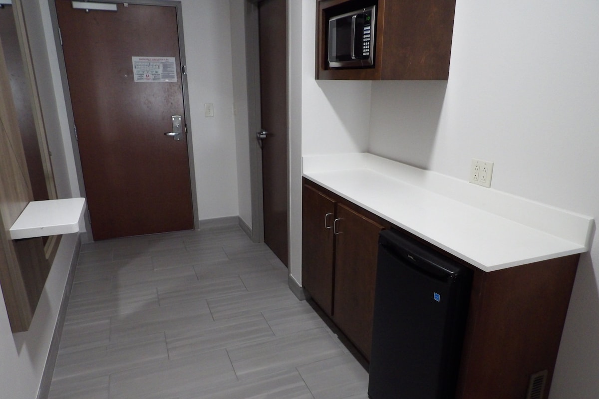 Una cocina equipada con microondas, lavavajillas y una puerta con un cartel.