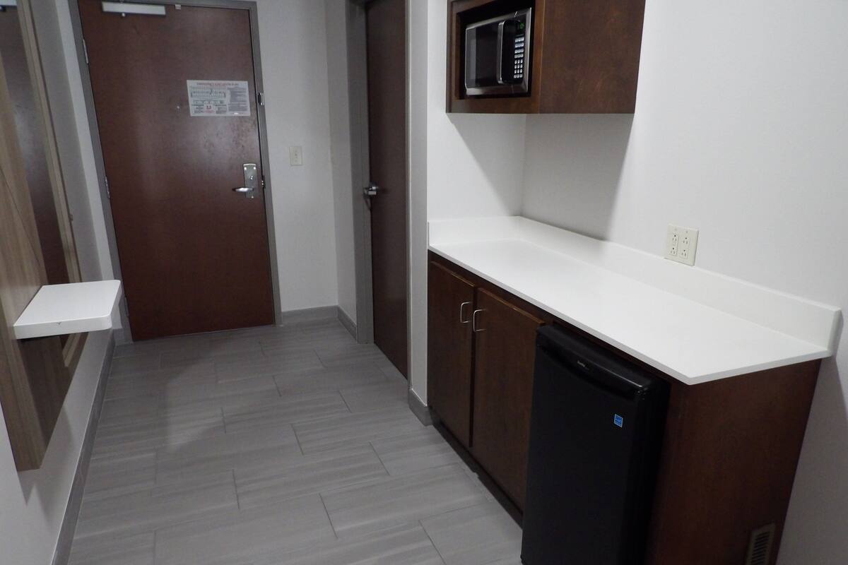 Una cocina equipada con microondas, lavavajillas y una puerta con un cartel.