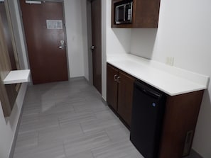 A kitchen with a microwave, a dishwasher, and a door with a sign. - Holiday Inn Express & Suites Huntsville Airport by IHG (Madison)