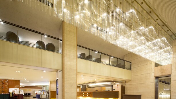 A spacious lobby with a modern design, featuring a reception desk, seating area, and a high ceiling with decorative lighting. - Castle Plaza Hotel (Nagoya)