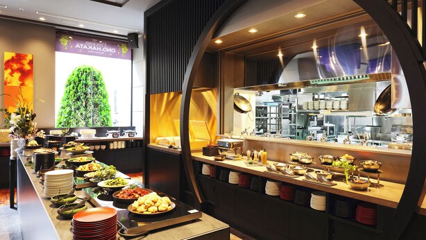 A buffet setup with various food items and a kitchen area in the background. - The Royal Park Hotel Fukuoka (Fukuoka)