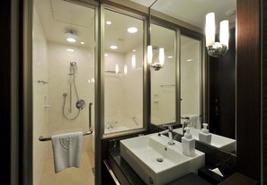 A modern bathroom with a glass-enclosed shower, a large mirror, and a white sink with a soap dispenser. - The Royal Park Hotel Fukuoka (Fukuoka)