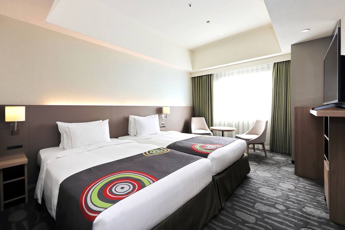 Ein Hotelzimmer mit einem großen Bett, einem Schreibtisch, einem Stuhl und einem Fernseher.