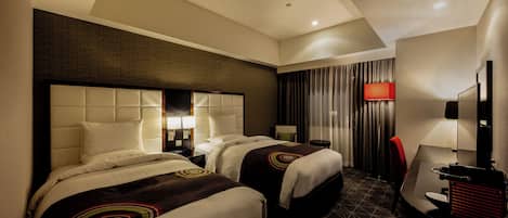A hotel room with two beds, a desk, a chair, a TV, and a red lamp.