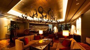 A modern lounge area with sofas, a coffee table, and a bar with shelves of bottles. - The Royal Park Hotel Fukuoka (Fukuoka)