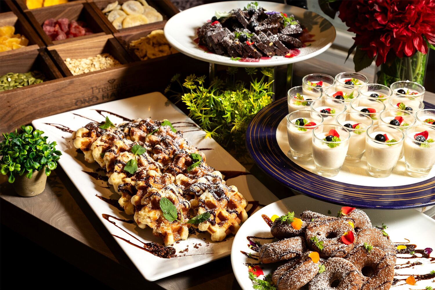 A variety of desserts on a table, including waffles, chocolate cake, and small cups of dessert.
