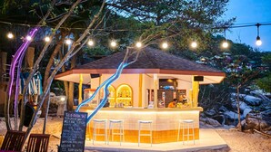 A small, open-air bar with a tiled counter and stools, surrounded by trees and rocks. -  Lub d Koh Tao Tanote Bay (Koh Tao)