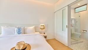 A hotel room with a bed, a nightstand, a wall-mounted lamp, a glass shower enclosure, and a door leading to the bathroom. -  Lub d Koh Tao Tanote Bay (Koh Tao)