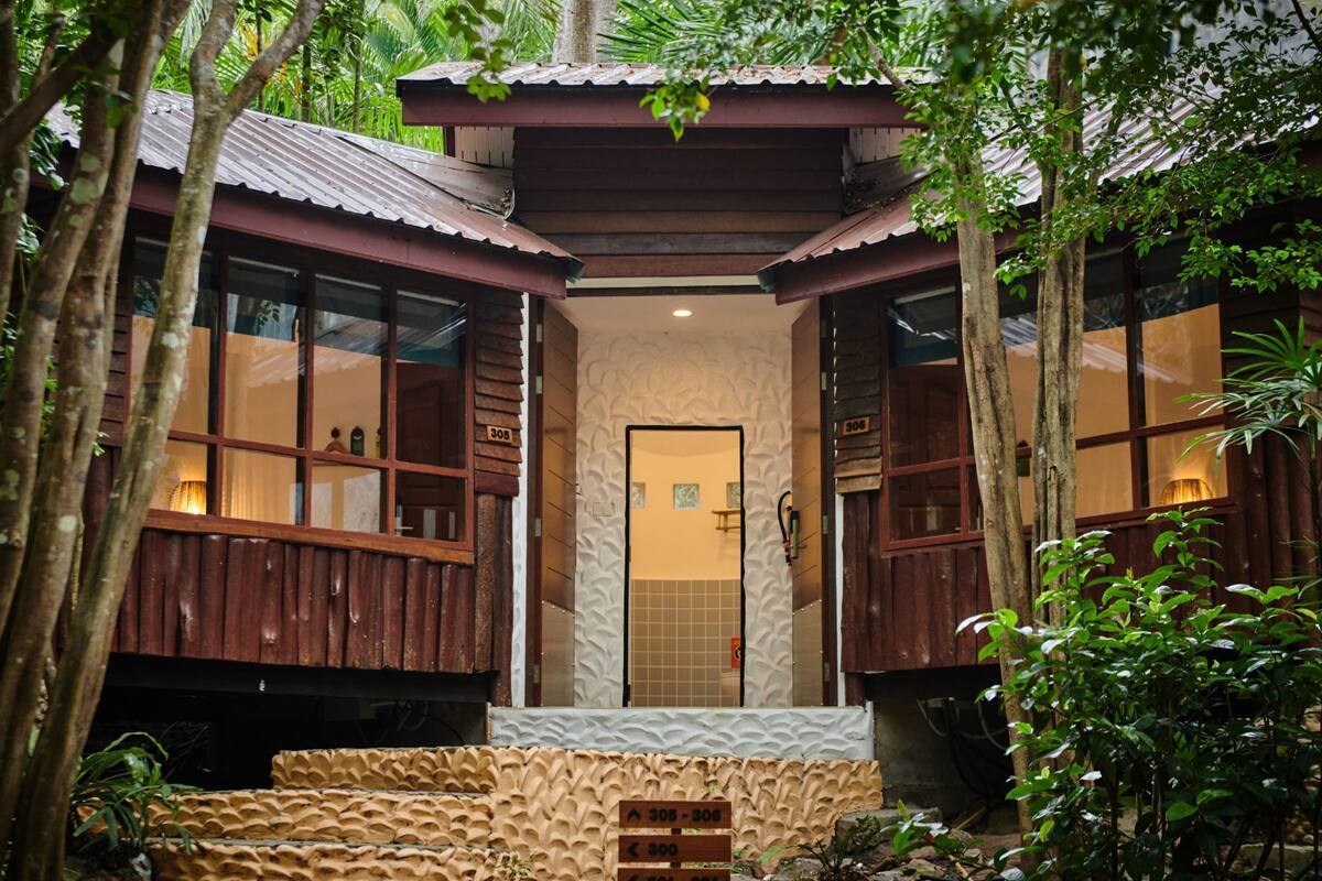 A traditional wooden structure with a central entrance, flanked by two wings with large windows.