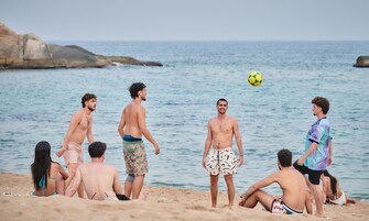Un grupo de personas en la playa jugando con un balón de fútbol.