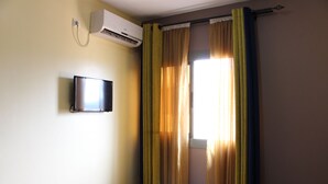 A hotel room with a bed, an air conditioning unit, and curtains. - Prestige Hotel (Yaoundé)