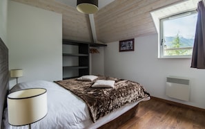 A bedroom with a bed, a lamp, a window with a view, and a heater.