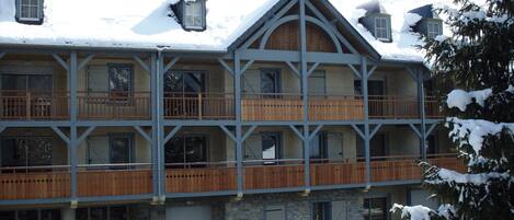 Una cabaña de varios pisos con balcones de madera y paredes de piedra, rodeada de nieve.