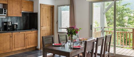A modern kitchen with wooden cabinets and a dining area with a table set for two.