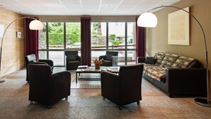 A modern lobby with a sofa, two armchairs, a coffee table, and a large window with curtains. - Résidence Lagrange Vacances Le Clos Saint Hilaire (Saint-Lary-Soulan)