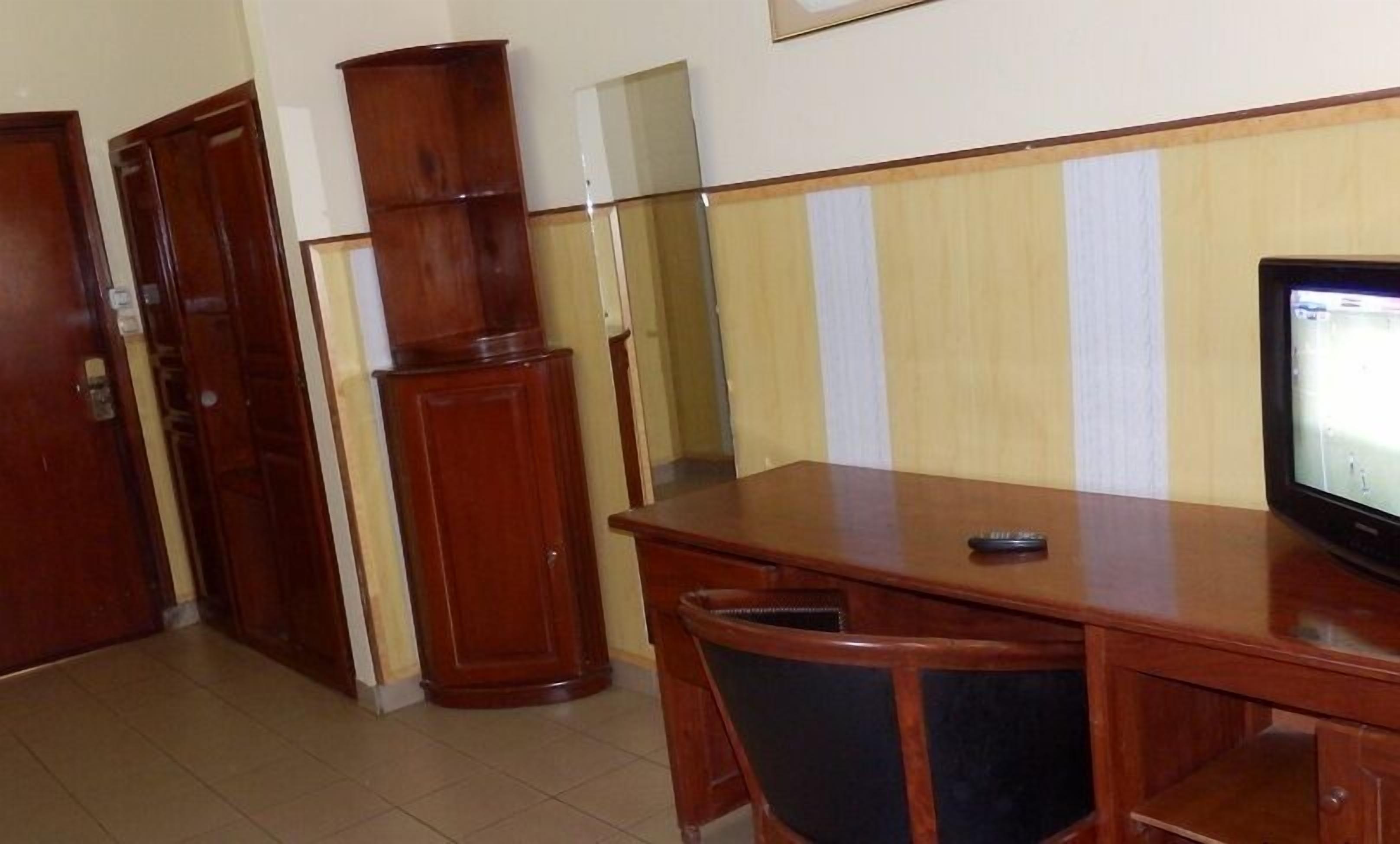 A room with a wooden desk, a chair, a television, and a cabinet.