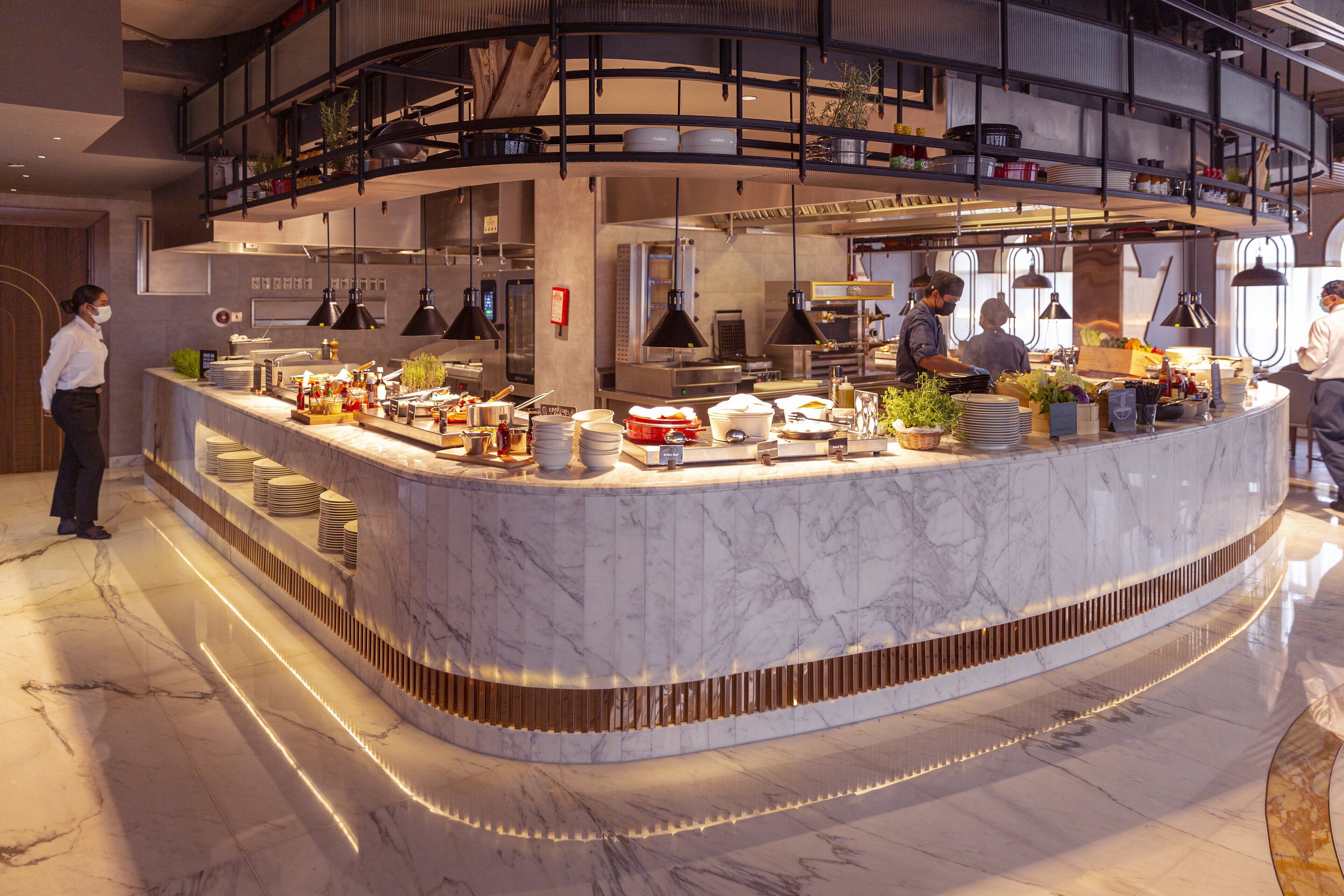 A modern kitchen with a marble countertop, overhead lighting, and a mezzanine level.