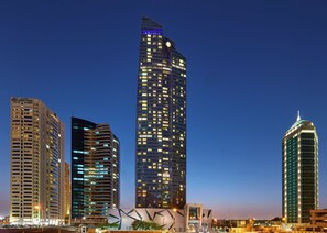 A high-rise building with a distinctive curved top, surrounded by other modern buildings. - InterContinental Doha The City by IHG (Doha)