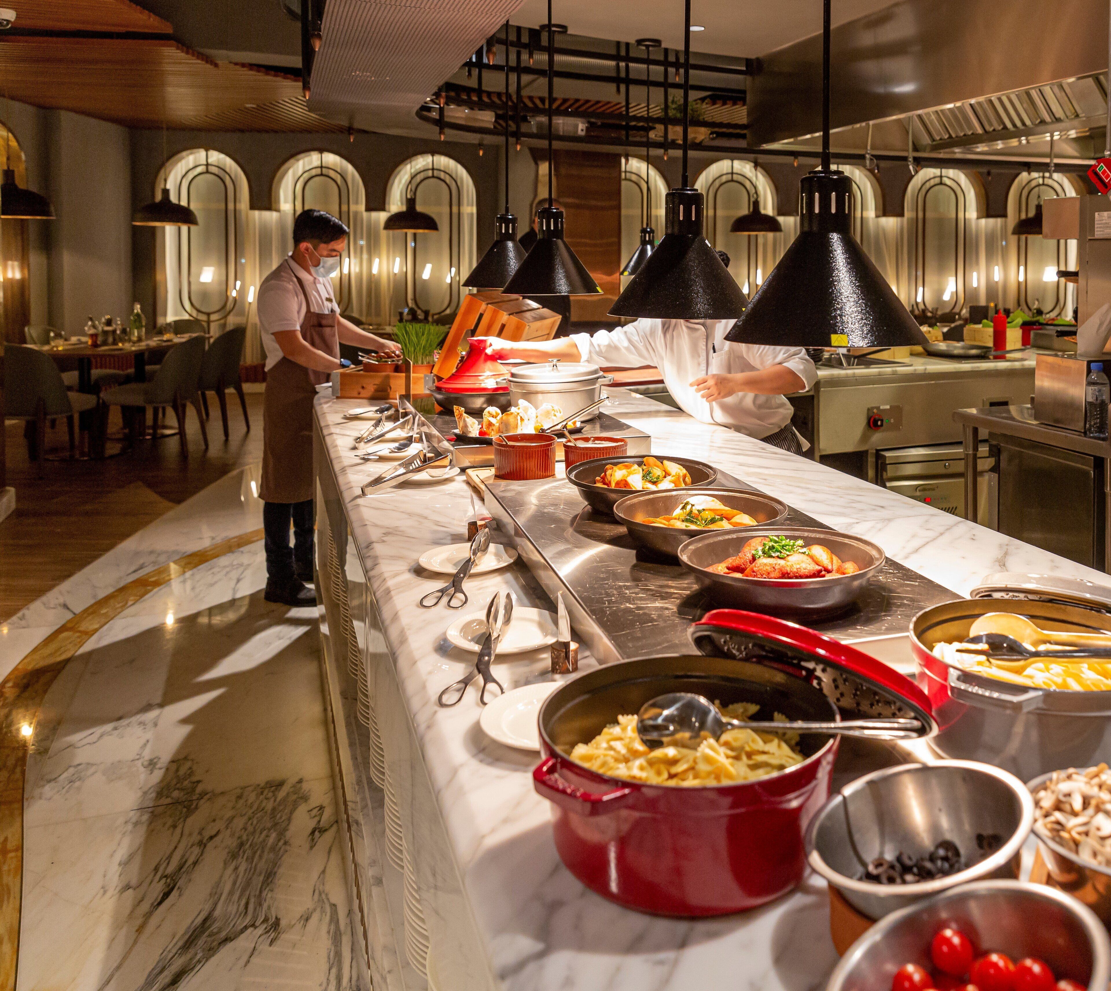 Un buffet proposant divers plats et couverts, disposés sur un comptoir en marbre.