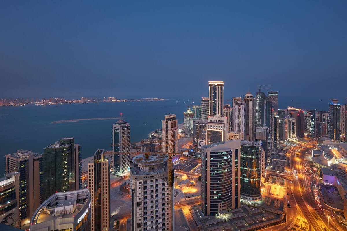 A high-rise cityscape with modern architecture, a waterfront, and busy roads.