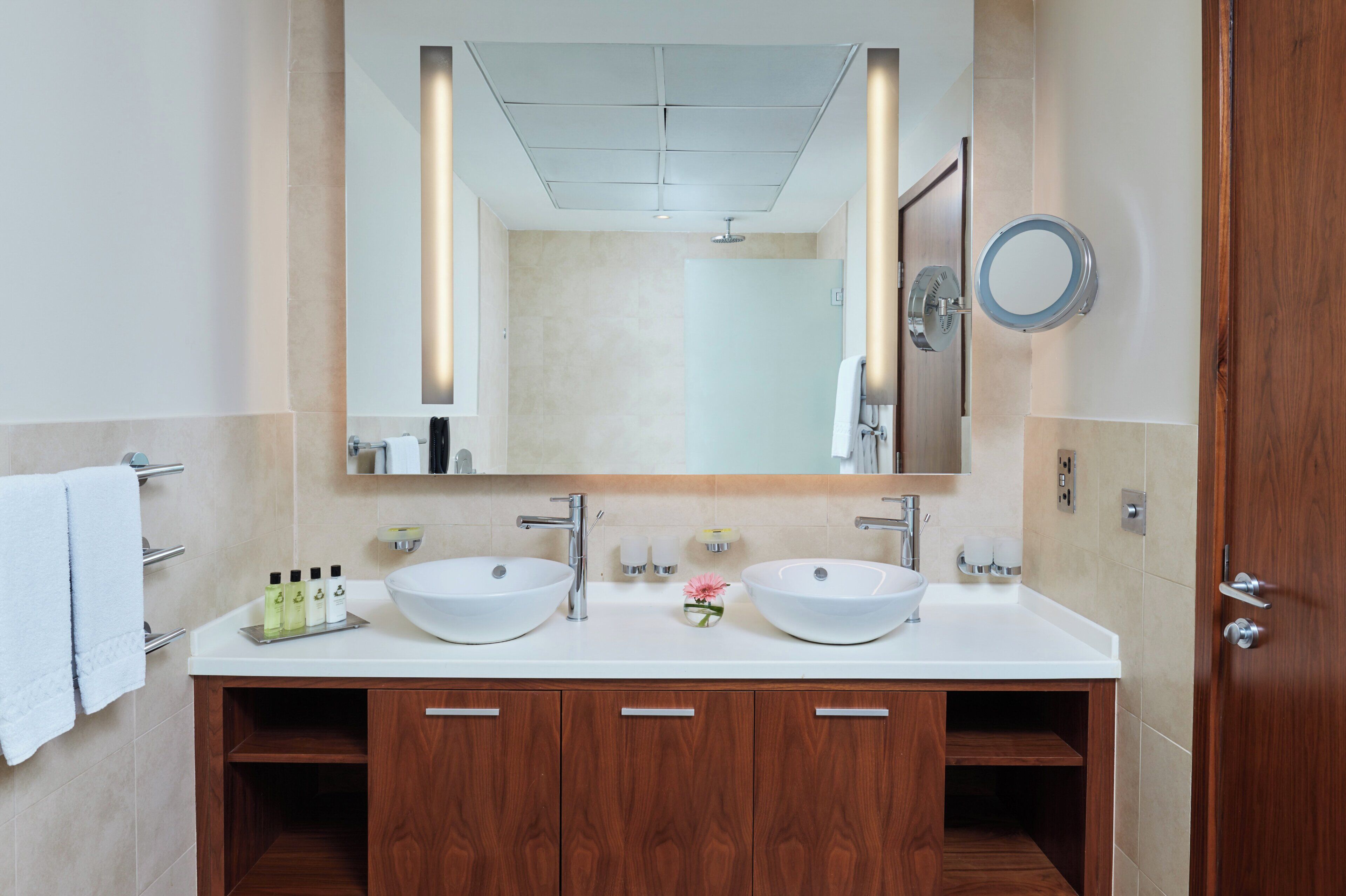 A bathroom with two sinks, a large mirror, and wooden cabinets.