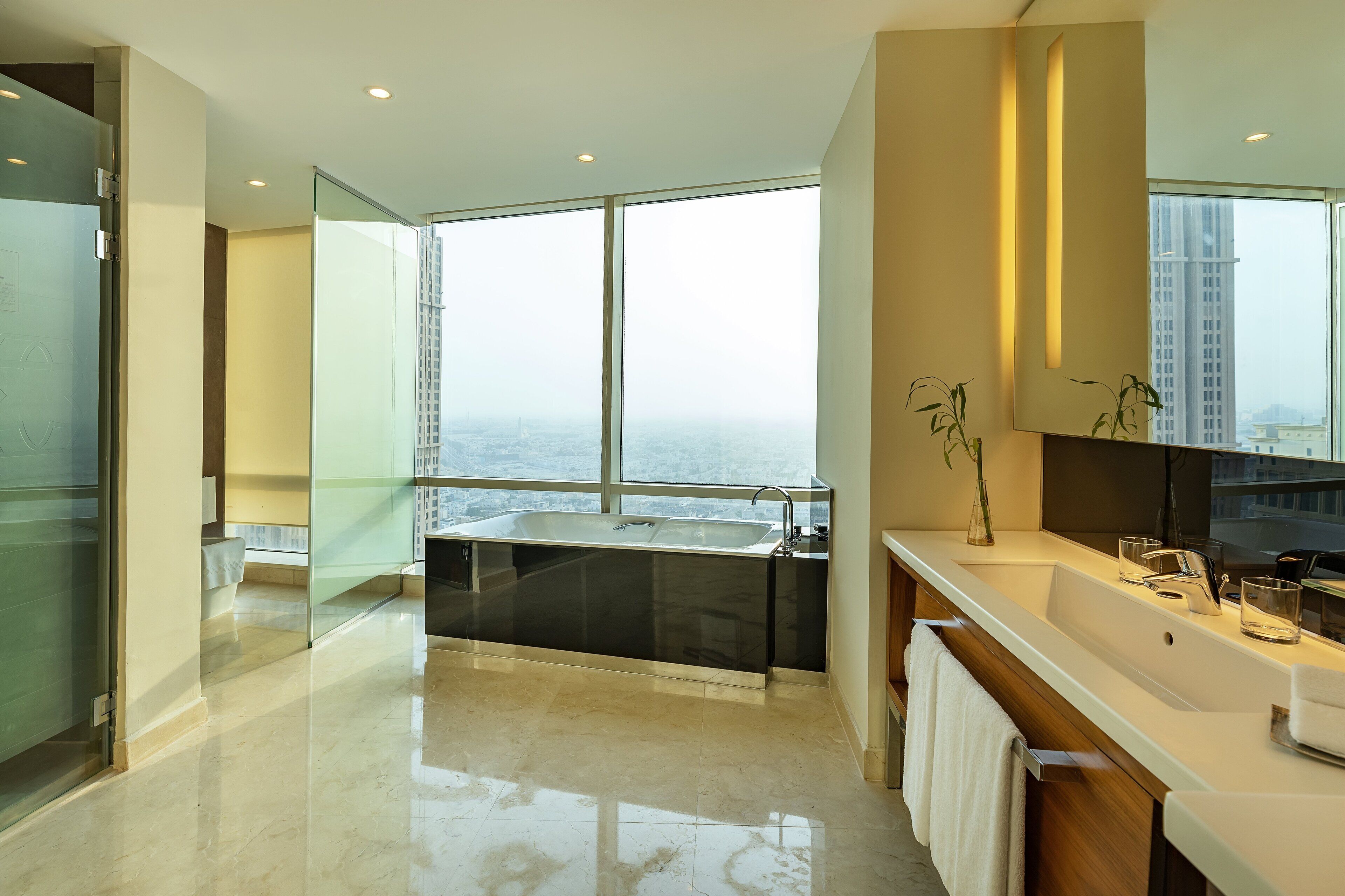 A modern bathroom with a large window, a bathtub, and a vanity with a mirror.