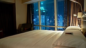 Hotelkamer met een groot raam en uitzicht op de stad 's nachts.