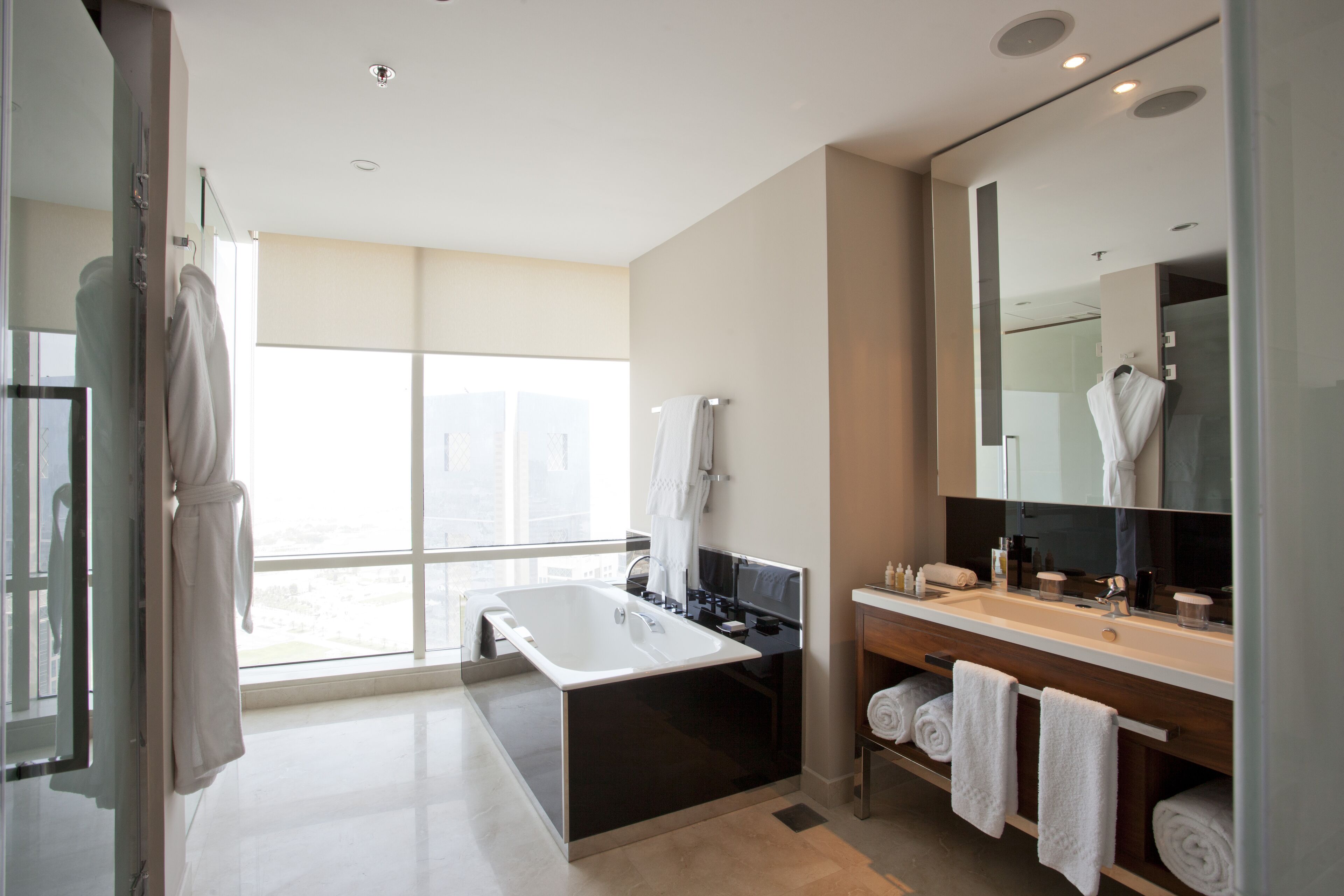 A modern bathroom with a large bathtub, a vanity with a mirror, and a window providing a view of the outdoors.