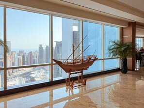 A spacious lobby with large windows offering a city view, a wooden ship model, and a potted plant. - InterContinental Doha The City by IHG (Doha)