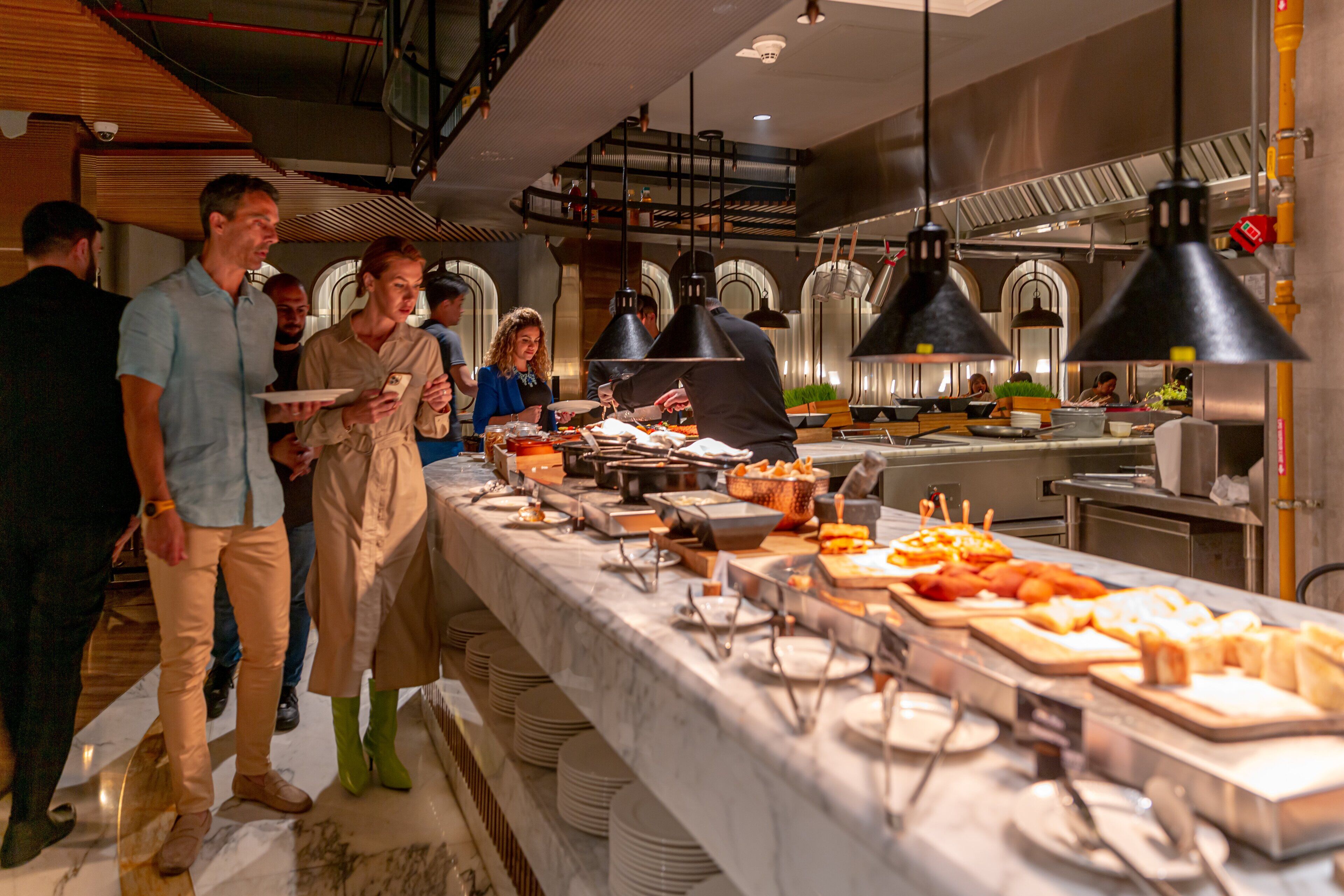 Disposição de buffet com diversos alimentos e utensílios de servir.