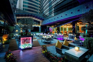 Un salón interior con jardín, zonas de estar, una fuente de agua y vistas al exterior del edificio.