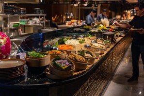 A buffet with various food items and a person serving. - InterContinental Doha The City by IHG (Doha)