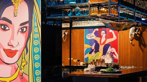 A bar area with shelves of bottles and glasses, a wooden counter, and a colorful mural on the wall. - InterContinental Doha The City by IHG (Doha)