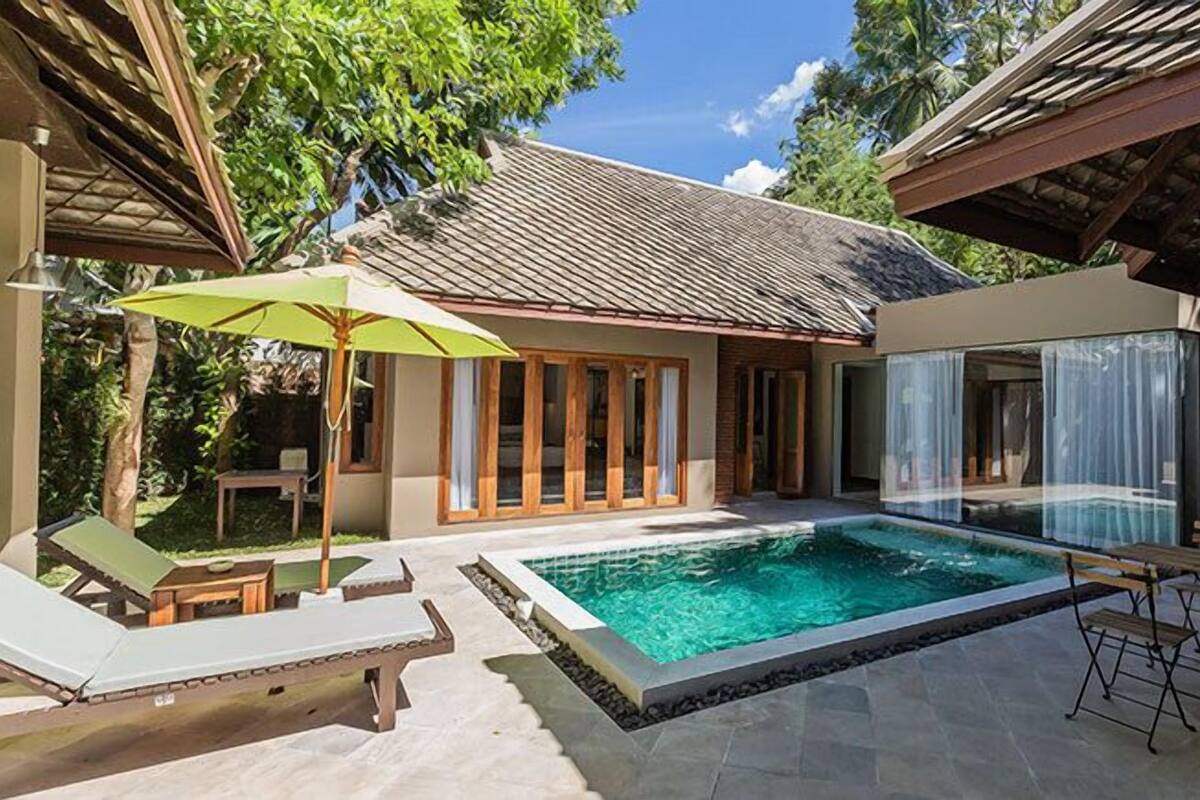 A poolside area with a clear pool, lounge chairs, and a table.