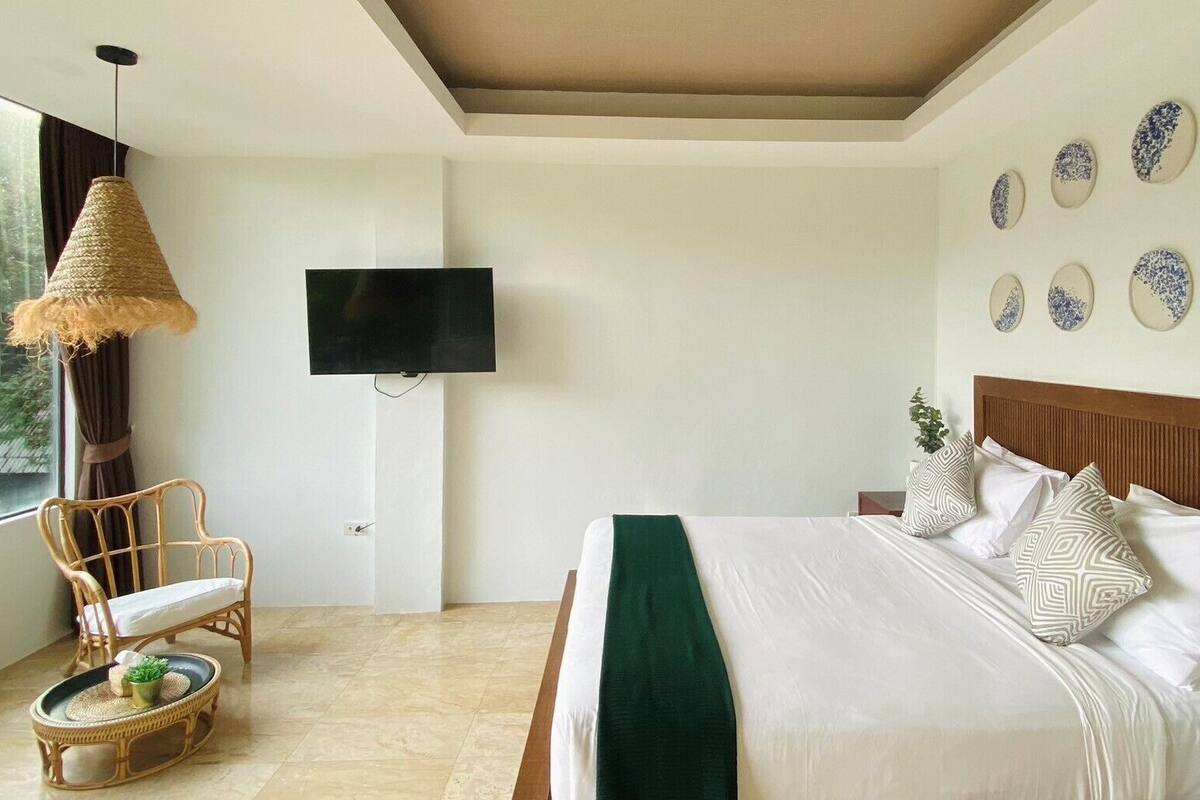 A bedroom with a bed, a television, a chair, and decorative wall plates.